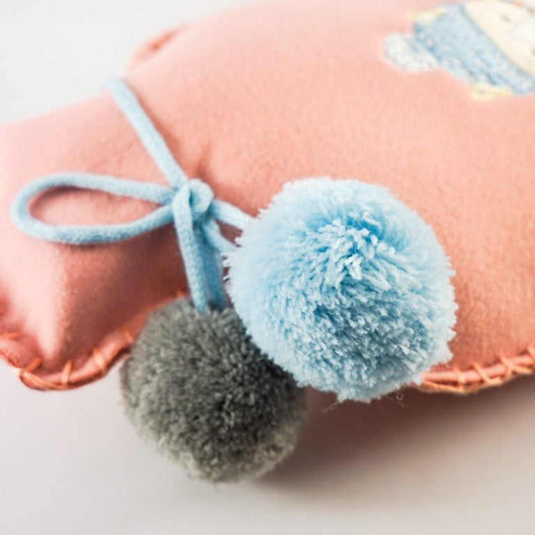 A grey and a blue colour pom pom tied to the hot water bottle's neck.